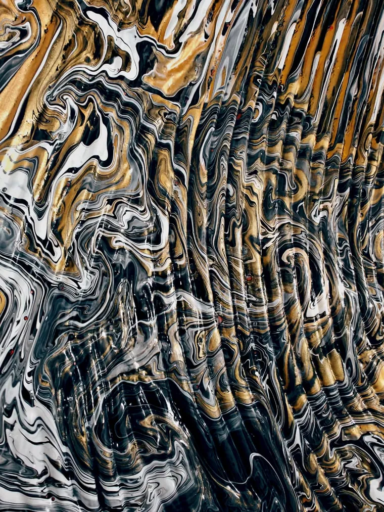 A close view of a poured painting dominated by metallic gold: broad gold bands and eddies across the upper half, folding down into black and white marbling below, the surface rippled like a seam of ore in rock.